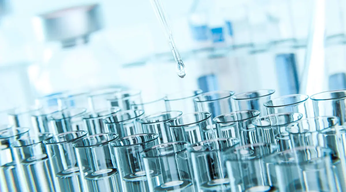 Laboratory glassware and a pipette dispensing a clear droplet during cannabinoid refining