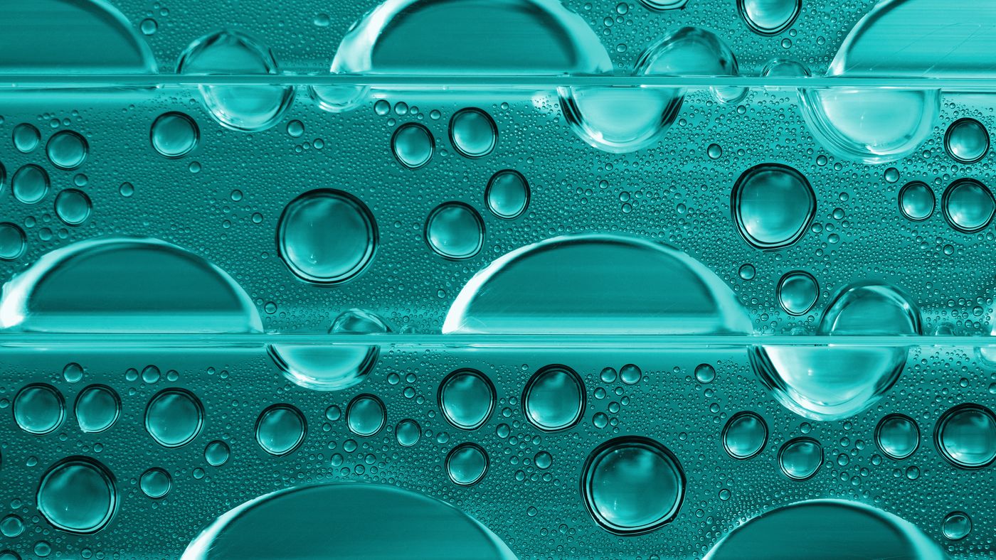 Macro view of water droplets on a cool teal surface