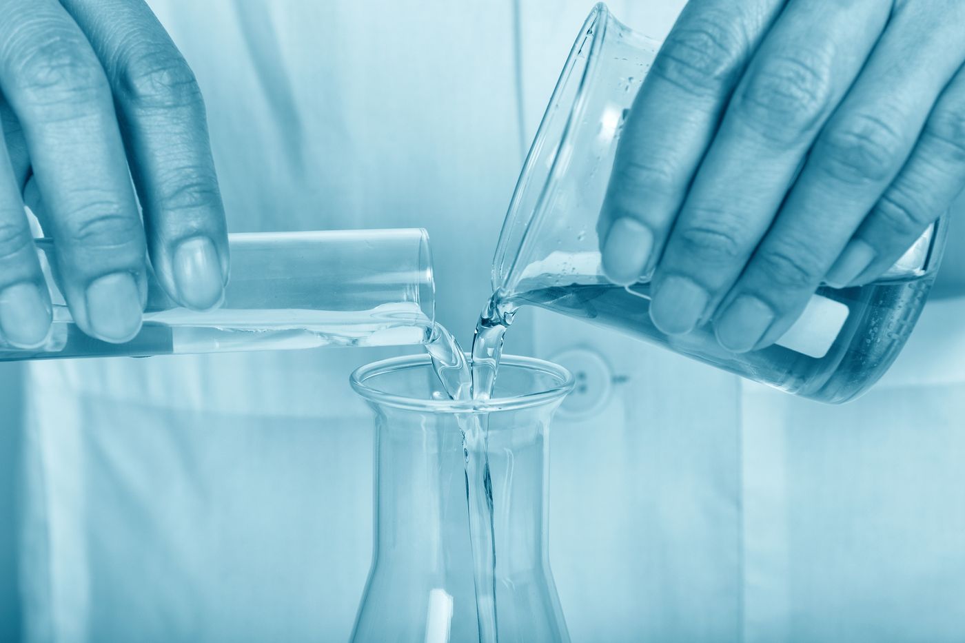 Clear liquid being poured into laboratory glassware under even light